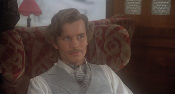 Movie still from “Murder on the Orient Express” (1974), directed by Sidney Lumet – A man sitting in a chair wearing a suit and tie; Close Up shot, Low angle