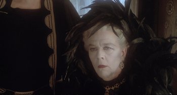 Movie still from “Murder on the Orient Express” (1974), directed by Sidney Lumet – An older woman wearing a black dress with feathers on her head; Close Up shot, Over the shoulder angle
