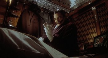 Movie still from “Murder on the Orient Express” (1974), directed by Sidney Lumet – A man sitting in front of an open book in a room; Medium shot, High angle