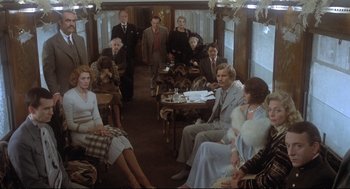 Movie still from “Murder on the Orient Express” (1974), directed by Sidney Lumet – A group of people sitting in a train car; Wide shot, High angle