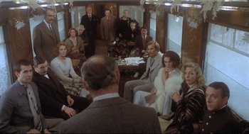 Movie still from “Murder on the Orient Express” (1974), directed by Sidney Lumet – A group of people sitting in a train car; Wide shot, High angle