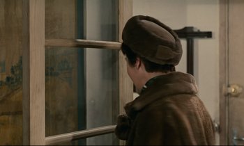 Movie still from “Muriel” (1963), directed by Alain Resnais – A man wearing a hat looking out of a window; Close Up shot, Over the shoulder angle