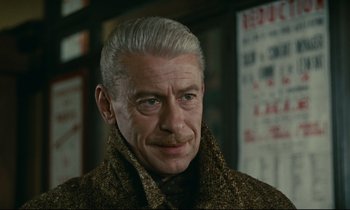 Movie still from “Muriel” (1963), directed by Alain Resnais – An older man wearing a coat and a tie; Close Up shot, Low angle