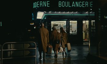 Movie still from “Muriel” (1963), directed by Alain Resnais – A group of people walking down a street at night; Wide shot, High angle