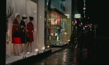Movie still from “Muriel” (1963), directed by Alain Resnais – A group of people standing on the side of a street; Extreme Wide shot, High angle