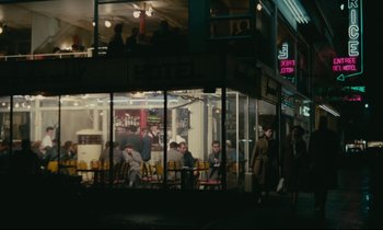 Movie still from “Muriel” (1963), directed by Alain Resnais – People are sitting outside of a restaurant at night; Extreme Wide shot, High angle