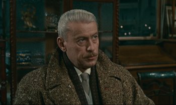 Movie still from “Muriel” (1963), directed by Alain Resnais – An older man in a coat and tie; Close Up shot, Low angle