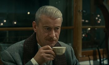 Movie still from “Muriel” (1963), directed by Alain Resnais – An older man drinking a cup of coffee; Close Up shot, Over the shoulder angle