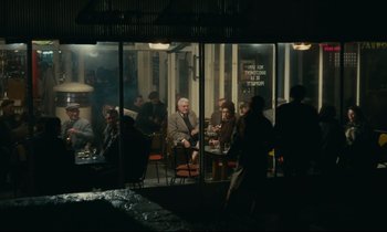 Movie still from “Muriel” (1963), directed by Alain Resnais – A group of people sitting at a table outside of a restaurant; Wide shot, High angle