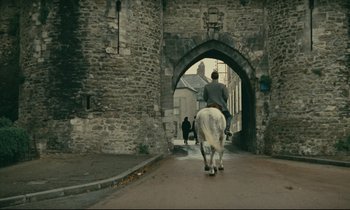 Movie still from “Muriel” (1963), directed by Alain Resnais – A man riding a horse down a street; Extreme Wide shot, Over the shoulder angle