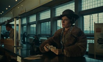 Movie still from “Muriel” (1963), directed by Alain Resnais – A man sitting at a table holding a stack of money; Medium shot, Low angle