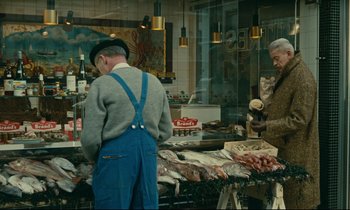 Movie still from “Muriel” (1963), directed by Alain Resnais – Two men standing in front of a display of fish; Wide shot, High angle