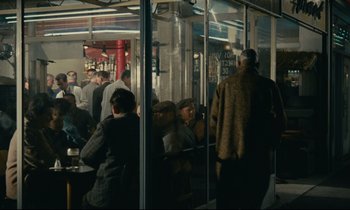 Movie still from “Muriel” (1963), directed by Alain Resnais – A group of people standing outside of a building; Wide shot, High angle