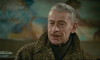 Movie still from “Muriel” (1963), directed by Alain Resnais – An older man wearing a coat and a tie; Close Up shot, Low angle