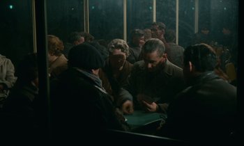 Movie still from “Muriel” (1963), directed by Alain Resnais – A group of people standing around each other in a room; Medium shot, High angle