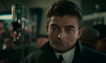 Movie still from “Muriel” (1963), directed by Alain Resnais – A person wearing a suit and tie; Close Up shot, Over the shoulder angle