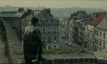 Movie still from “Muriel” (1963), directed by Alain Resnais – A man standing on top of a building looking down on a street; Wide shot, High angle