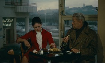 Movie still from “Muriel” (1963), directed by Alain Resnais – A man and a woman sitting at a table with a plate of food; Medium shot, High angle