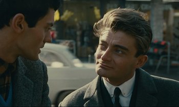 Movie still from “Muriel” (1963), directed by Alain Resnais – A man in a suit and tie talking to another man in a suit and tie; Close Up shot, Over the shoulder angle