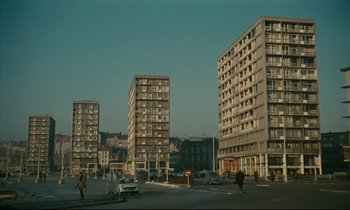 Movie still from “Muriel” (1963), directed by Alain Resnais – A group of tall buildings on a street; Extreme Wide shot, Low angle
