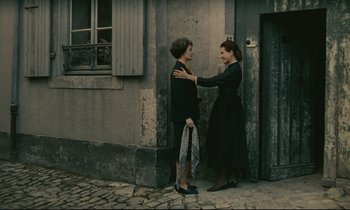 Movie still from “Muriel” (1963), directed by Alain Resnais – Two women standing next to each other on the sidewalk; Wide shot, High angle