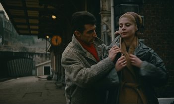 Movie still from “Muriel” (1963), directed by Alain Resnais – A man helping a woman put on a scarf; Medium shot, High angle