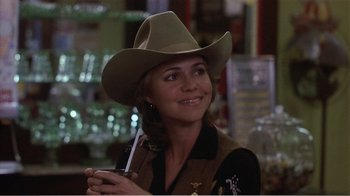 Movie still from “Murphy's Romance” (1985), directed by Martin Ritt – A woman wearing a cowboy hat holding a glass of wine; Close Up shot, Over the shoulder angle