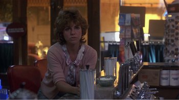 Movie still from “Murphy's Romance” (1985), directed by Martin Ritt – A woman sitting at a table in front of drinks; Medium shot, Over the shoulder angle