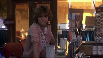 Movie still from “Murphy's Romance” (1985), directed by Martin Ritt – A woman sitting at a table with a glass of beer; Medium shot, Over the shoulder angle