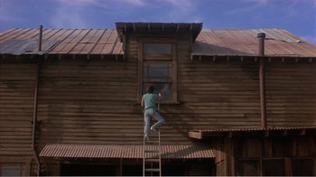 Movie still from “Murphy's Romance” (1985), directed by Martin Ritt – A man on a ladder painting a wooden house; Wide shot, Low angle