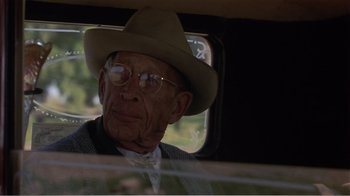 Movie still from “Murphy's Romance” (1985), directed by Martin Ritt – An old man wearing glasses and a hat driving a car; Close Up shot, Over the shoulder angle