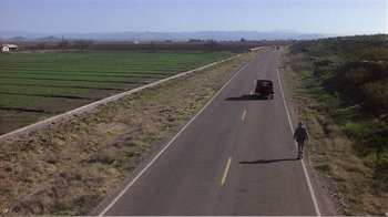 Movie still from “Murphy's Romance” (1985), directed by Martin Ritt – A man walking down a road with a red truck on the side of the road; Extreme Wide shot, High angle