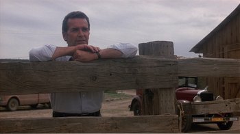 Movie still from “Murphy's Romance” (1985), directed by Martin Ritt – A man leaning on a wooden fence near a red truck; Medium shot, Low angle