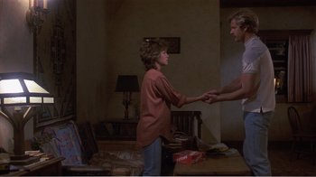 Movie still from “Murphy's Romance” (1985), directed by Martin Ritt – A man and a woman holding hands in a living room; Wide shot, Low angle