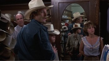 Movie still from “Murphy's Romance” (1985), directed by Martin Ritt – A group of people standing in front of a mirror wearing cowboy hats; Medium shot, Over the shoulder angle