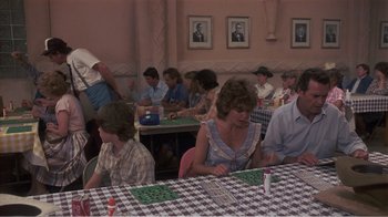 Movie still from “Murphy's Romance” (1985), directed by Martin Ritt – A group of people sitting at a table playing a game; Medium shot, High angle