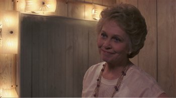 Movie still from “Murphy's Romance” (1985), directed by Martin Ritt – An older woman smiling for the camera in front of lights; Close Up shot, Over the shoulder angle