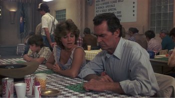 Movie still from “Murphy's Romance” (1985), directed by Martin Ritt – A man and a woman sitting at a table playing dominoes; Medium shot, Over the shoulder angle