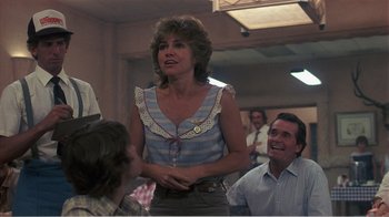 Movie still from “Murphy's Romance” (1985), directed by Martin Ritt – A woman standing in front of a group of people; Medium shot, Over the shoulder angle