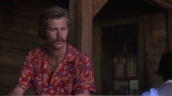 Movie still from “Murphy's Romance” (1985), directed by Martin Ritt – A man in a red shirt is sitting in a room; Close Up shot, Over the shoulder angle