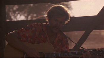 Movie still from “Murphy's Romance” (1985), directed by Martin Ritt – A man playing a guitar in the sunlight; Close Up shot, Low angle