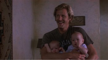 Movie still from “Murphy's Romance” (1985), directed by Martin Ritt – A man holding two babies in his arms and smiling; Medium shot, Low angle
