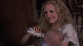 Movie still from “Murphy's Romance” (1985), directed by Martin Ritt – A woman holding a baby while using a hair dryer; Close Up shot, Over the shoulder angle