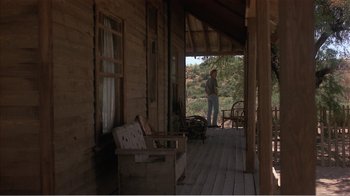 Movie still from “Murphy's Romance” (1985), directed by Martin Ritt – A man standing on the porch of an old house; Wide shot, Low angle