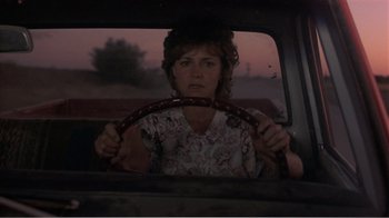 Movie still from “Murphy's Romance” (1985), directed by Martin Ritt – A woman sitting in the back seat of a car holding a steering wheel; Medium shot, Over the shoulder angle