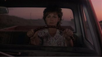 Movie still from “Murphy's Romance” (1985), directed by Martin Ritt – A woman sitting in the back seat of a car holding a steering wheel; Medium shot, Over the shoulder angle