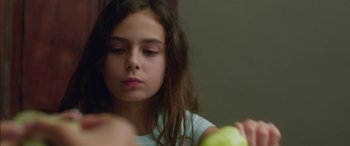 Movie still from “Mustang” (2015), directed by Deniz Gamze Ergüven – A young girl holding an apple in front of her face; Close Up shot, Over the shoulder angle