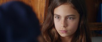 Movie still from “Mustang” (2015), directed by Deniz Gamze Ergüven – A young girl with long brown hair and green eyes looking at the camera; Close Up shot, Over the shoulder angle