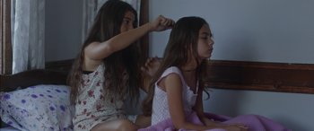 Movie still from “Mustang” (2015), directed by Deniz Gamze Ergüven – Two young girls sitting on a bed combing each other's hair; Medium shot, High angle