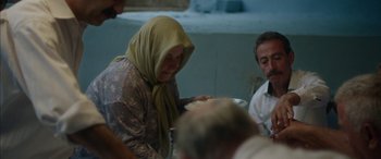 Movie still from “Mustang” (2015), directed by Deniz Gamze Ergüven – An older woman wearing a headscarf is sitting at a table; Medium shot, Over the shoulder angle